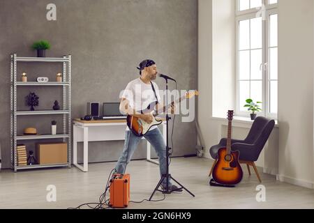 Il musicista rock cantava nel microfono e suonava con la chitarra elettrica collegata all'amplificatore Foto Stock