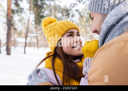 Uomo sorridente che abbraccia la ragazza in outfit invernale all'aperto Foto Stock