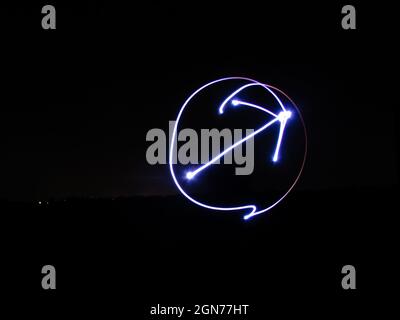 freccia e cerchio chiaro su sfondo nero scattati con tecnica fotografica a lunga esposizione Foto Stock