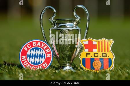 27 agosto 2021 Baviera, Monaco di Baviera. Gli emblemi dei club calcistici FC Barcelona e FC Bayern Monaco e della UEFA Champions League Cup sul prato verde o Foto Stock