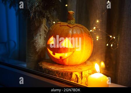 La zucca scolpita guarda fuori dalla finestra. Jack Lantern, concetto di Halloween. Foto Stock