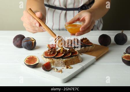 Donna spalma miele su bruschetta con fichi Foto Stock