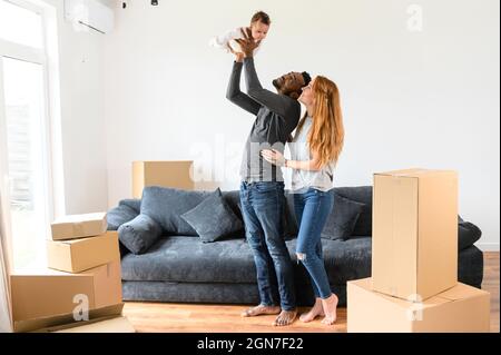 Felice famiglia misto-corsa si è riallocato in nuova casa, afro-americano marito e moglie caucasica in piedi con una figlia biraciale carino circondato scatole di cartone Foto Stock