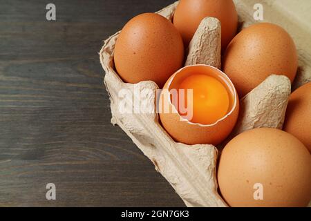 Uova fresche organiche con uno di guscio aperto in una scatola di cartone Foto Stock