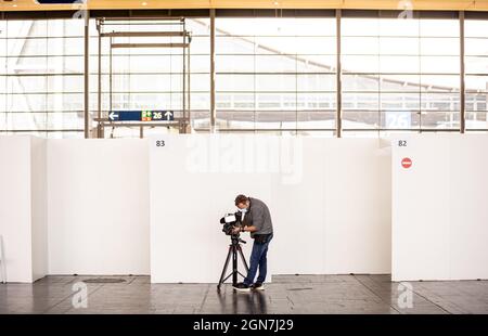 23 settembre 2021, bassa Sassonia, Hannover: Un cameraman filma un'area d'attesa presso il centro di vaccinazione sul terreno espositivo. Il centro comune di vaccinazione della città e della regione di Hannover presso la zona espositiva cesserà le operazioni il 27.09.2021 dopo circa otto mesi. Foto: Moritz Frankenberg/dpa Foto Stock