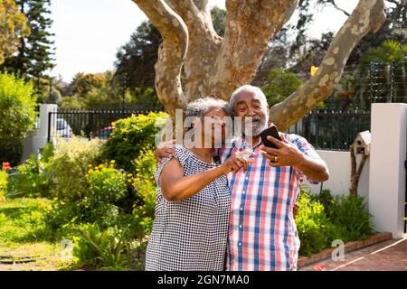 Felice coppia di anziani afroamericani che prendono selfie in giardino Foto Stock