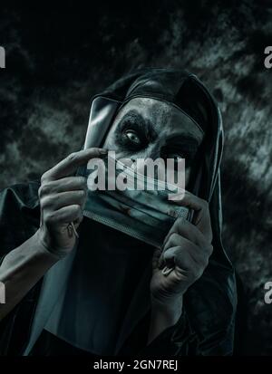 primo piano di una suora malvagia spaventosa, in una tipica abitudine bianca e nera, mettendo sopra o togliendo una maschera di faccia usa e getta sporca Foto Stock