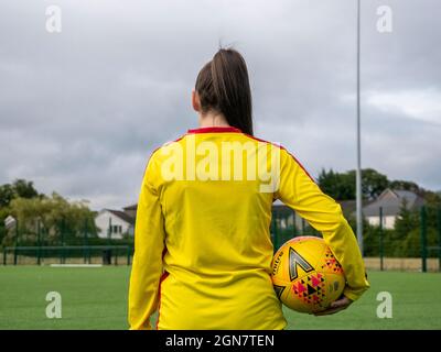 Glasgow, Scozia, Regno Unito. 14 luglio 2020: Una calciatore femminile che tiene un calcio mentre la ha di nuovo alla macchina fotografica. Foto Stock