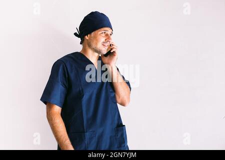 Infermiera, medico o veterinario in uniforme blu in una finestra in un ospedale, parlando al telefono cellulare. Concetto di medicina, ospedale e assistenza sanitaria. Foto Stock