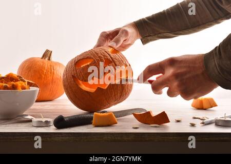 Dettaglio di uomo che intagliano e svuotano una zucca per la festa di Halloween. Vista frontale. Composizione orizzontale. Foto Stock