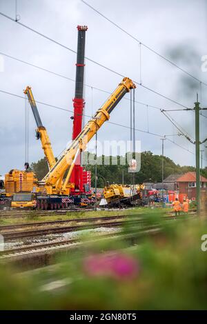 23 settembre 2021, bassa Sassonia, Emden: Le gru montate su autocarri vengono utilizzate per sollevare una gru per la costruzione di binari deragliati di peso superiore a 100 tonnellate. La gru per la costruzione di ferrovie è stata deragliata la scorsa settimana al molo di Borkum e ora deve essere recuperata. Foto: Sina Schuldt/dpa Foto Stock