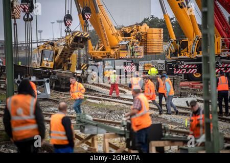 23 settembre 2021, bassa Sassonia, Emden: Le gru montate su autocarri vengono utilizzate per sollevare una gru per la costruzione di binari deragliati di peso superiore a 100 tonnellate. La gru per la costruzione di ferrovie è stata deragliata la scorsa settimana al molo di Borkum e ora deve essere recuperata. Foto: Sina Schuldt/dpa Foto Stock