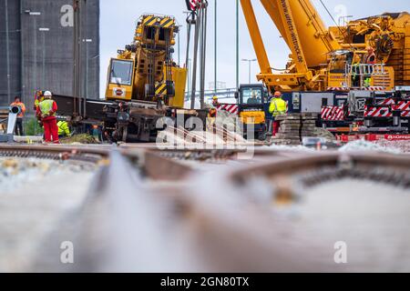 23 settembre 2021, bassa Sassonia, Emden: Le gru montate su autocarri vengono utilizzate per sollevare una gru per la costruzione di binari deragliati di peso superiore a 100 tonnellate. La gru per la costruzione di ferrovie è stata deragliata la scorsa settimana al molo di Borkum e ora deve essere recuperata. Foto: Sina Schuldt/dpa Foto Stock