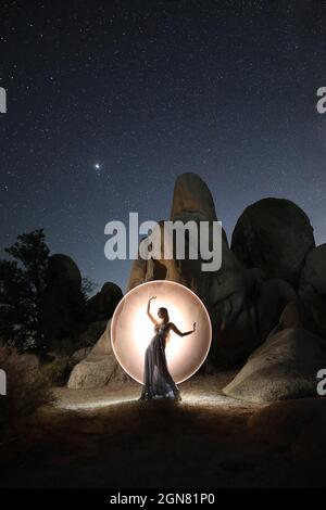 Modello dipinto di luce in posa con stelle nel deserto Foto Stock