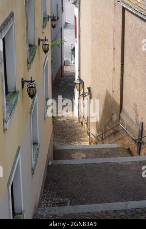 Scalinata stretta romantica in una città vecchia in Germania. Percorso con ciottoli tra vecchie facciate e storiche lampade di strada. Foto Stock