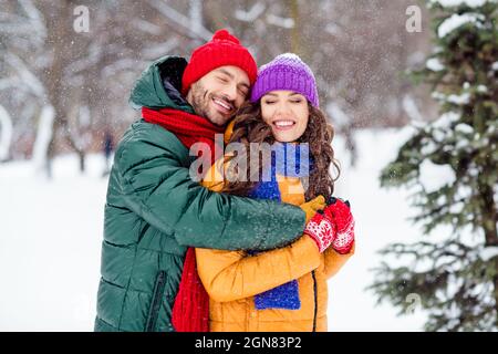 Foto di ragazza brillante sognante ragazzo vestito giubbotti sorridenti abbracciando godendo camminare neve all'aperto foresta Foto Stock