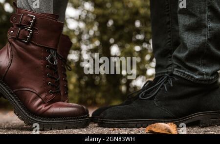 Piedi di coppia. L'uomo e la donna sono in piedi l'uno di fronte all'altro. Primo piano di scarpe in pelle scamosciata blu e stivali in pelle borgogna sulle punte delle dita. Primo piano. Foto Stock