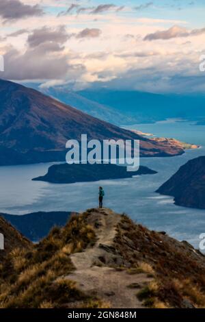 Colpo verticale di un uomo su una scogliera vicino al mare durante il tramonto Foto Stock