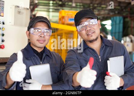 Due lavoratori in piedi con spettacolo dando i pollici in su Foto Stock