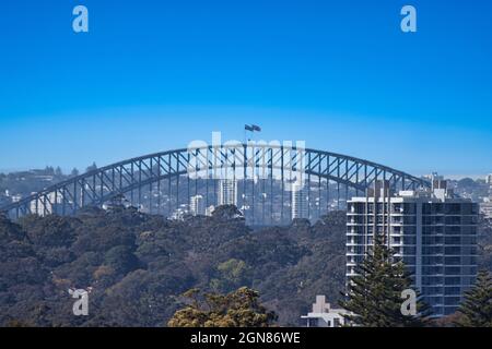 Foto panoramica del ponte in acciaio di Sydney, patrimonio dell'umanità dell'UNESCO, attraverso il porto sotto il cielo blu Foto Stock