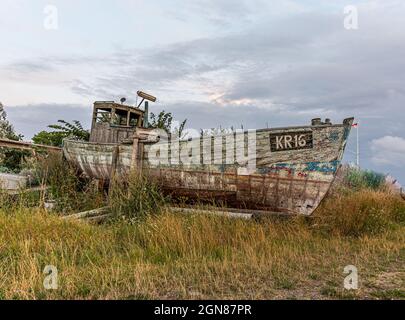 Un vecchio peschereccio dilapidato giacente sulla riva, coltivato in erba, Bisserup, Danimarca, 8 agosto; 2021 Foto Stock