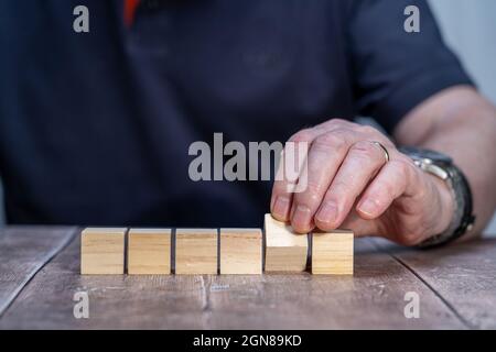 modello bianco mock su di sei cubi di blocco di legno , quinto cubo imperniato con un uomo sullo sfondo tenendo il blocco imperniato Foto Stock