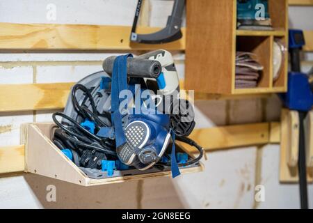 messa a fuoco selezionata in primo piano di un respiratore blu che si stende da una sega a immersione elettrica posizionata su un ripiano montato su un sistema di taglio francese Foto Stock