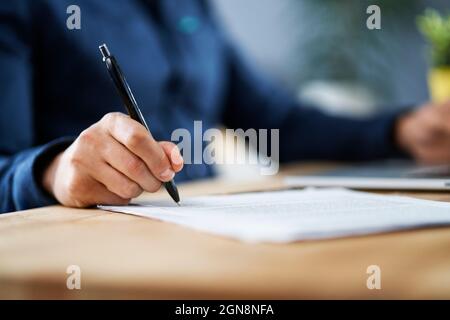 Uomo d'affari firma i documenti mentre lavora da casa Foto Stock