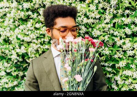 Bouquet odorante uomo d'affari di fronte alle piante da fiore Foto Stock