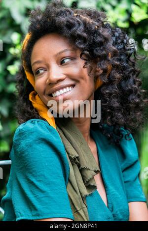 Giovane donna sorridente con capelli ricci neri Foto Stock