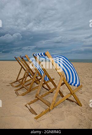 Sedie a sdraio a strisce blu e bianche sulla spiaggia Foto Stock