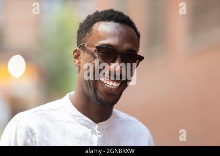 Giovane uomo in occhiali da sole sorridente durante il giorno Foto Stock