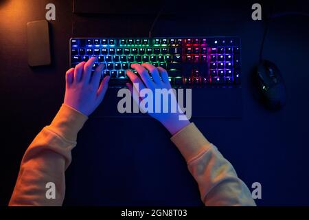 Ragazzo digitando su tastiera multicolore a tavola Foto Stock