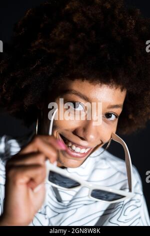 Donna sorridente con occhiali su sfondo nero Foto Stock