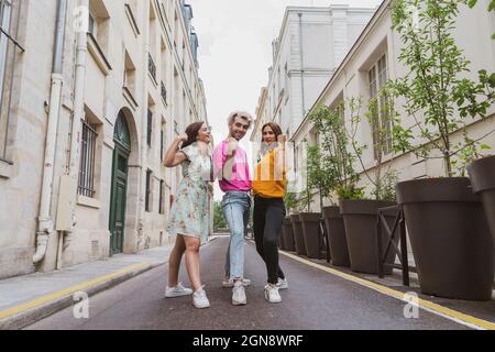 Yong uomo e donne che flettono le braccia mentre si trova in piedi per strada Foto Stock