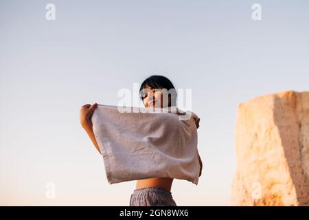 Giovane donna con asciugamano in spiaggia Foto Stock