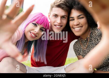 Uomo sorridente tra amici femminili che gesturano al parco Foto Stock