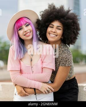 Felice giovane donna afrofroica abbracciante hipster femmina amico Foto Stock