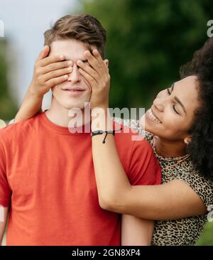 Giovane donna che copre il fidanzato occhi Foto Stock