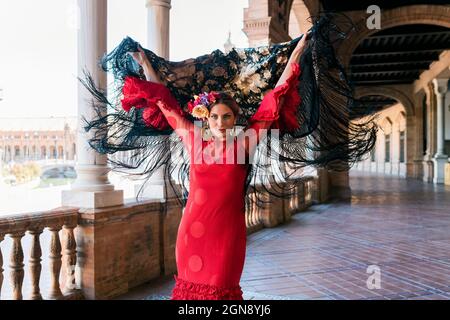 Artista flamenco femminile che tiene scialle con le mani sollevate al passaggio pedonale di Plaza De Espana a Siviglia, Spagna Foto Stock