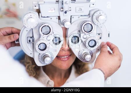 Optometristo maschile che controlla la paziente attraverso il forottero Foto Stock