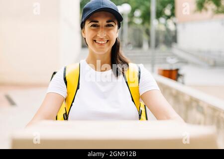 Donna di consegna sorridente con corriere che tiene il tappo Foto Stock