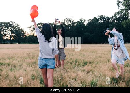 Gli amici fotografano con la macchina fotografica e il telefono cellulare al parco Foto Stock