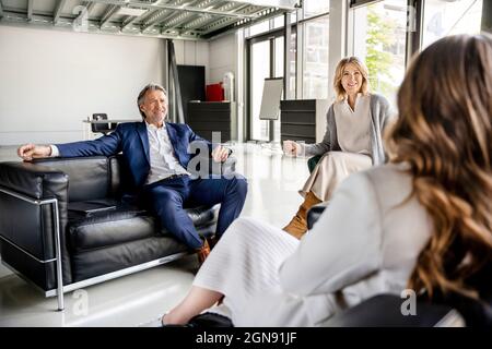 Sorridenti professionisti di sesso maschile e femminile che discutono durante la riunione in ufficio Foto Stock