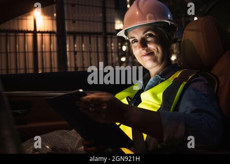 Ingegnere femminile sorridente con tablet digitale seduto in auto Foto Stock