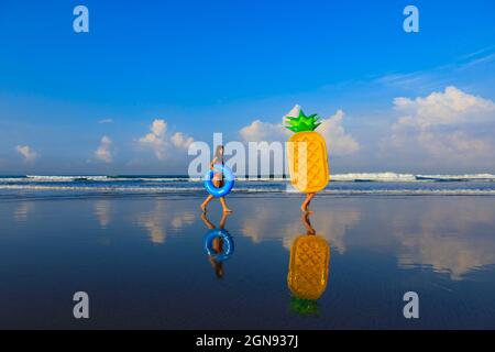 Donne con galleggianti che camminano in spiaggia Foto Stock