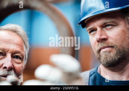 Lavoratore maturo che controlla le attrezzature mentre è in piedi da manager maschile nel settore Foto Stock