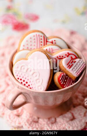 Shot studio di ciotola di miele, cucchiaia di miele e mini torte appena sfornate a forma di cuore Foto Stock