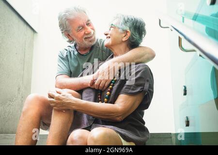 Coppia anziana che si abbraccia mentre si siede sui gradini Foto Stock
