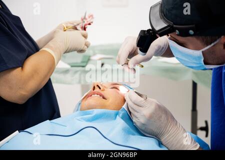 Il chirurgo sutura la palpebra dopo un intervento di chirurgia plastica Foto Stock